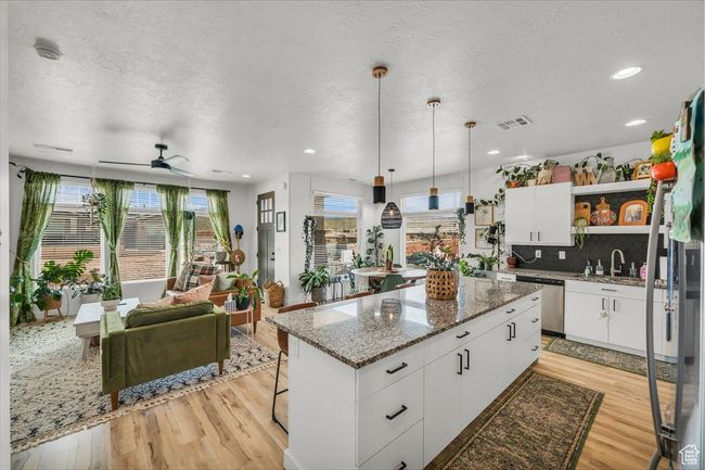 Kitchen with dishwasher, light wood-style floors, open shelves, and visible vents | Image 11