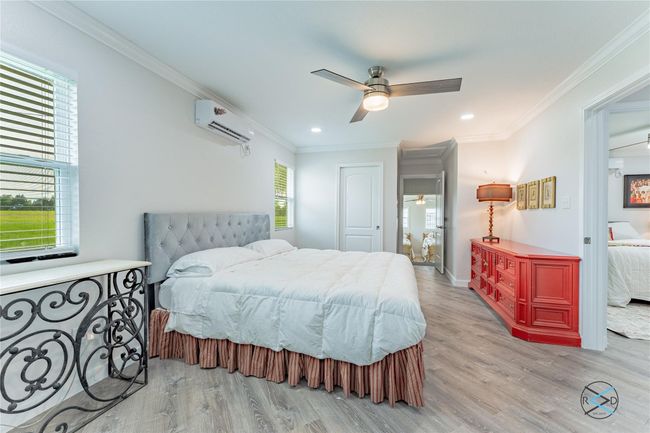 Bedroom featuring light wood-type flooring, an AC wall unit, ceiling fan, and crown molding | Image 18