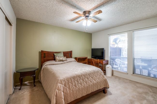 Bedroom with light colored carpet, a textured ceiling, a closet, and ceiling fan | Image 15