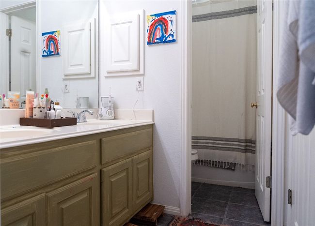 Full bathroom with double vanity, tile patterned floors, and a shower with shower curtain | Image 28
