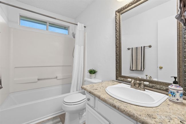 Bathroom with vanity, shower / bath combination with curtain, and a textured ceiling | Image 14
