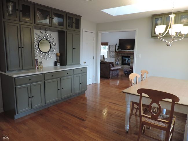 dining room with wood flooring, a skylight, a notable chandelier, and a fireplace | Image 12