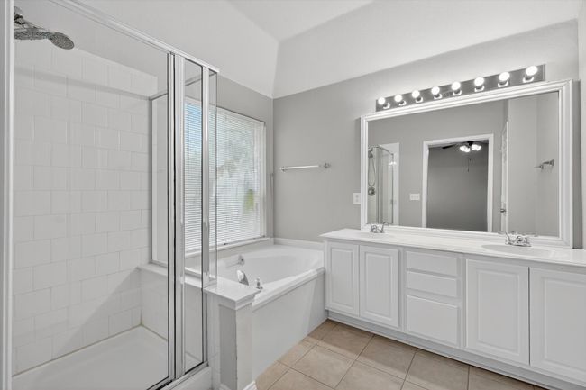 Primary bathroom with a stall shower, a bath, double vanity, tile patterned flooring, and a ceiling fan | Image 14
