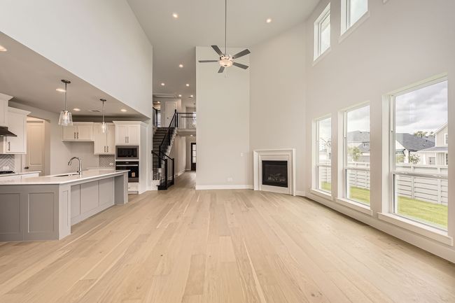 Kitchen with black oven, light wood-type flooring, built in microwave, a towering ceiling, and white cabinetry | Image 5