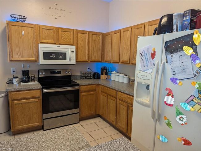 Kitchen with white appliances, light tile patterned floors, and brown cabinets | Image 21