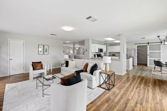 Living room featuring a barn door, light wood finished floors, baseboards, and stairway | Image 12