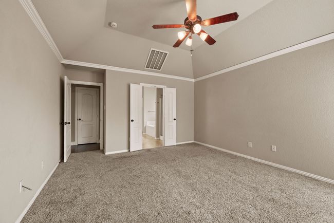 Unfurnished bedroom with crown molding, ensuite bathroom, lofted ceiling, carpet flooring, and visible vents | Image 20