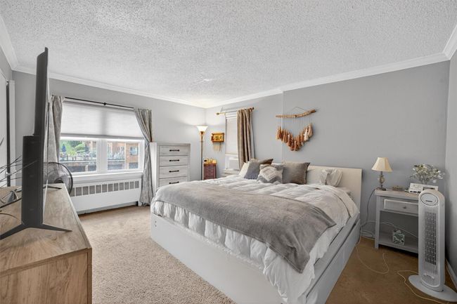 Carpeted bedroom featuring radiator, ornamental molding, and a textured ceiling | Image 15