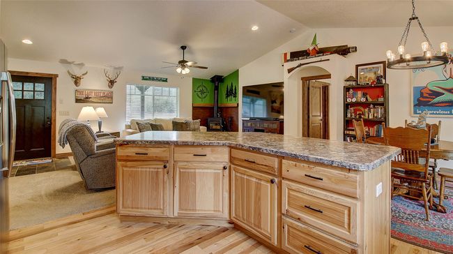 Kitchen featuring open floor plan, a wood stove, light brown cabinets, a ceiling fan, and light wood-style flooring | Image 9