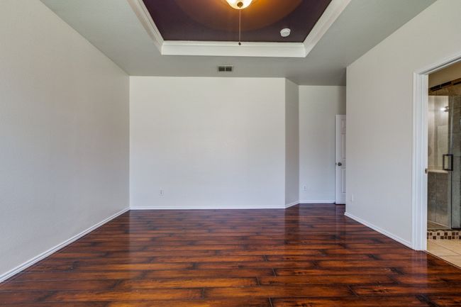 Empty room featuring a raised ceiling, wood finished floors, baseboards, and visible vents | Image 11