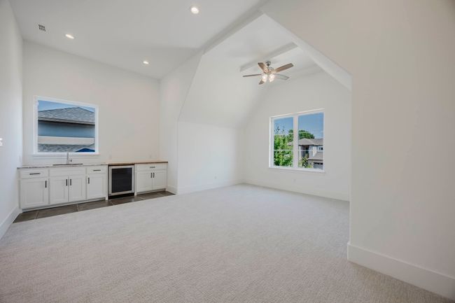 Unfurnished living room with light colored carpet, vaulted ceiling, recessed lighting, a ceiling fan, and beverage cooler | Image 25