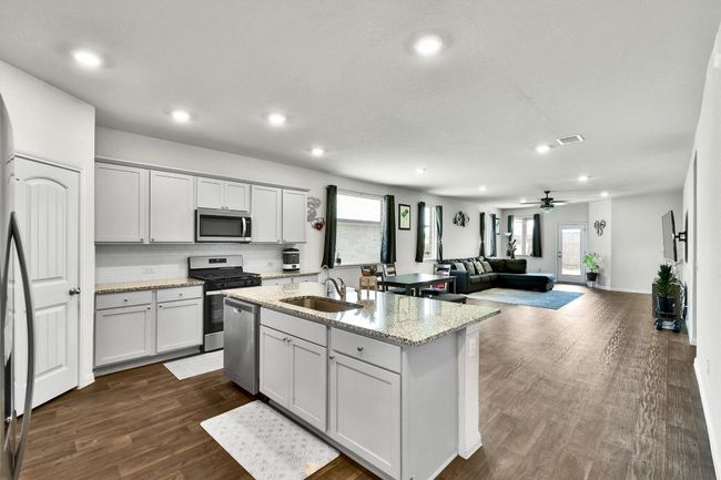 Kitchen featuring stainless steel appliances, a sink, recessed lighting, dark wood-type flooring, and light stone counters | Image 7