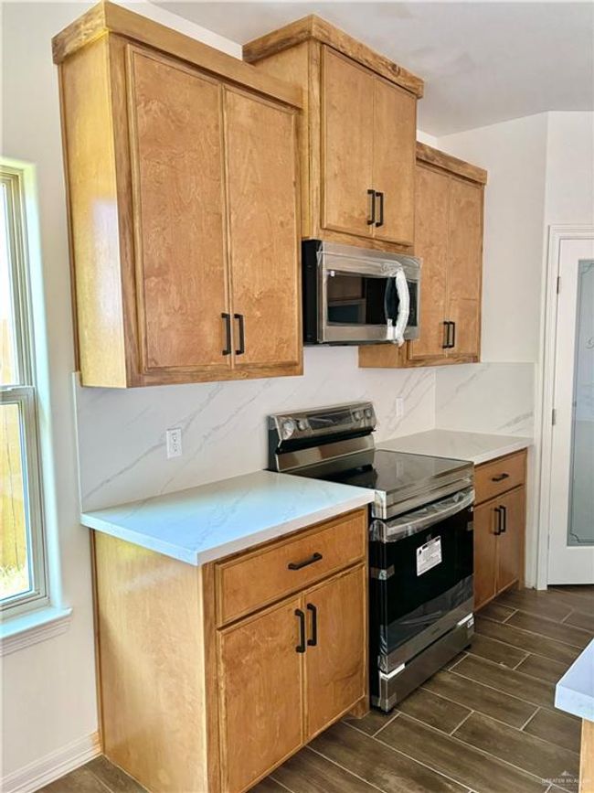Kitchen with decorative backsplash, stainless steel appliances, and wood finish floors | Image 6