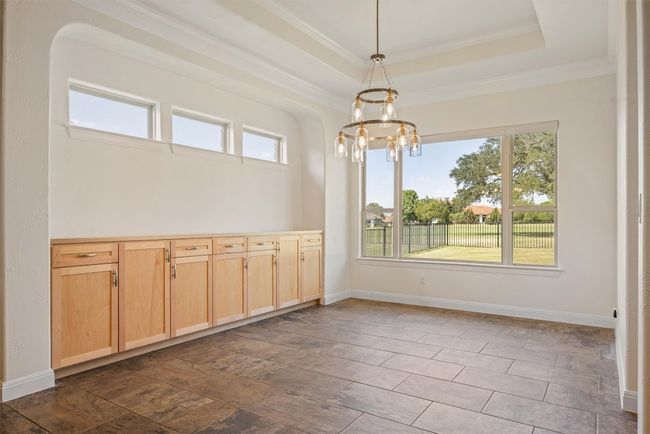 Oversized dining area has massive storage cabinetry, beautiful chandelier, tray ceiling and large picture window with golf course views | Image 21