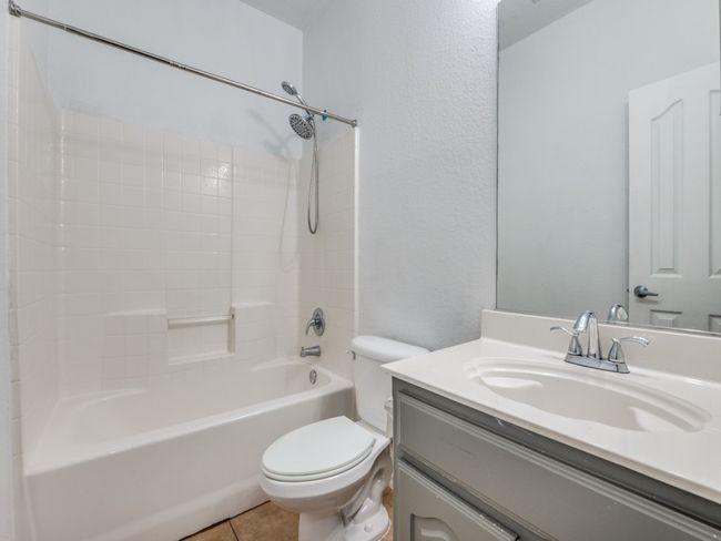 Bathroom featuring tile patterned flooring, shower / bathing tub combination, toilet, a textured wall, and vanity | Image 22