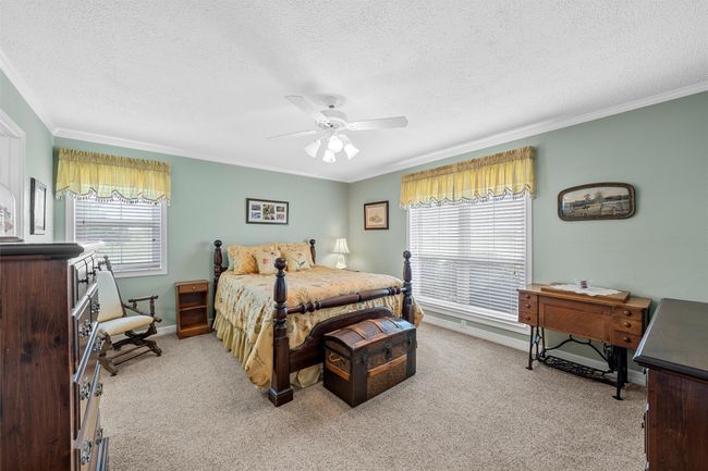 Bedroom featuring light colored carpet, a textured ceiling, crown molding, and a ceiling fan | Image 14