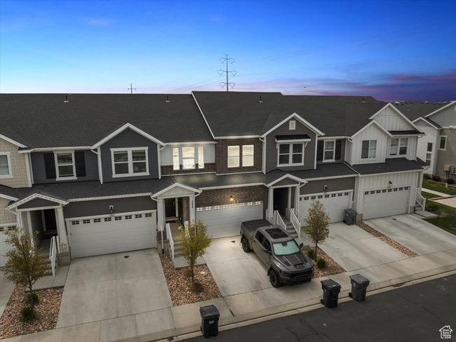 Townhome / multi-family property featuring board and batten siding, a shingled roof, driveway, and a garage | Image 31