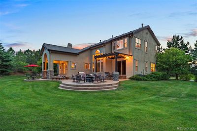 This home’s expansive backyard features a beautifully lit patio and a large, flat grassy lawn, perfect for outdoor play. | Image 3