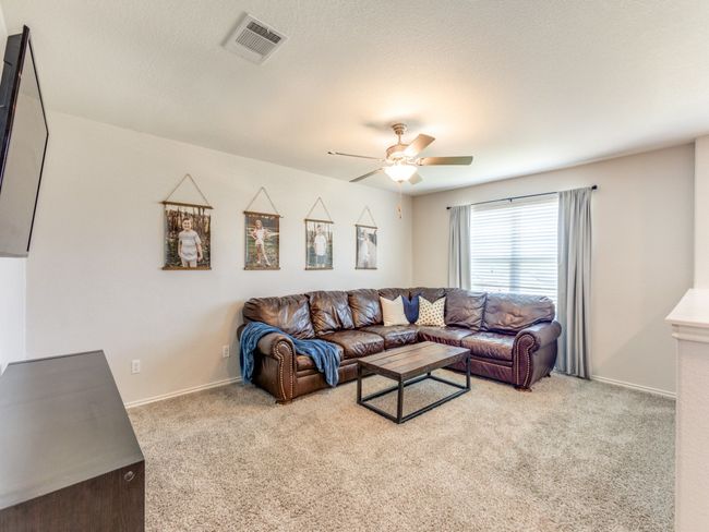 Carpeted living room featuring a ceiling fan and baseboards | Image 23