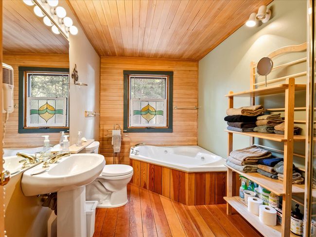 Full bath featuring toilet, wood ceiling, hardwood / wood-style floors, a garden tub, and wood walls | Image 26