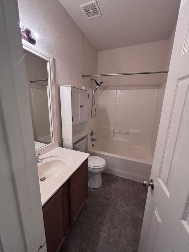 Bathroom with vanity, shower combination, tile patterned flooring, and a textured wall | Image 9