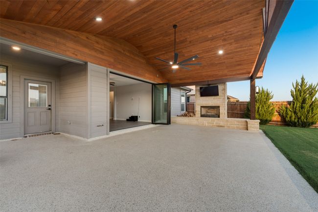 View of custom patio with an outdoor stone fireplace, and ceiling fan | Image 18