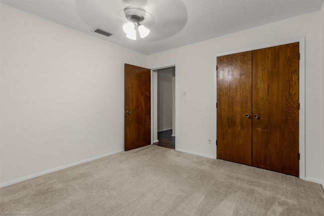 Unfurnished bedroom with carpet flooring, a closet, baseboards, ceiling fan, and a textured ceiling | Image 22