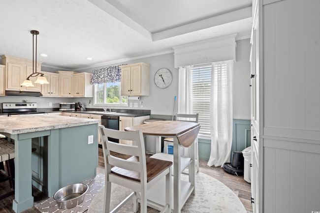 Kitchen featuring stainless steel appliances, cream cabinets, ornamental molding, under cabinet range hood, and light wood-type flooring | Image 10