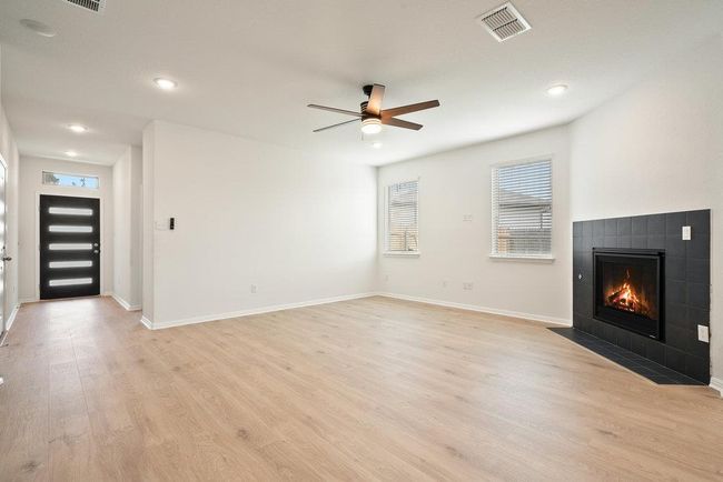 Unfurnished living room featuring a fireplace, light wood-style floors, ceiling fan, and recessed lighting | Image 8