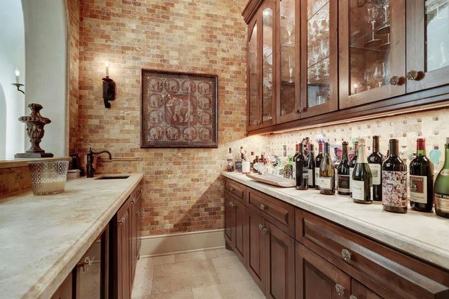 Bar off of the living room has limestone counters, groin vaulted ceiling, stone walls, ice maker, refrigerator, custom cabinets, scones , under counter lighting, Baretti cabinet hardware throughout the home and chandelier. | Image 13