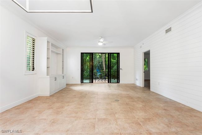 Empty room with crown molding, built in shelves, a healthy amount of sunlight, and ceiling fan | Image 35
