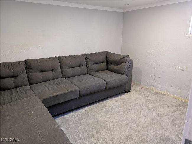 Living area with a textured wall, carpet flooring, and crown molding | Image 17