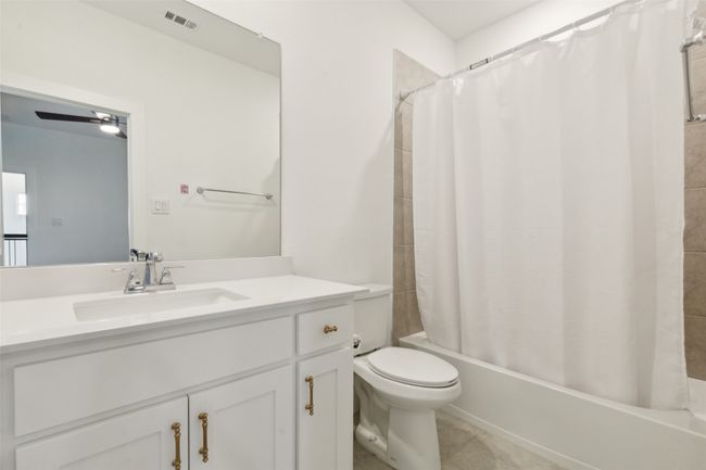 Full bath with toilet, shower / bathtub combination with curtain, vanity, and tile patterned flooring | Image 24