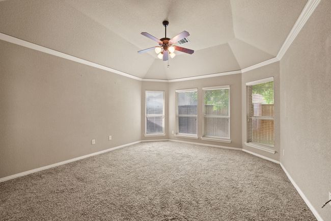 Carpeted spare room featuring crown molding, a ceiling fan, a textured ceiling, a textured wall, and lofted ceiling | Image 19