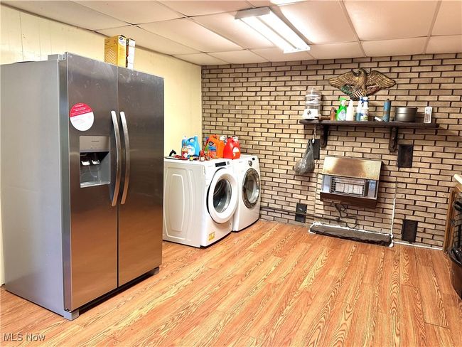 Laundry area with brick wall, wood finished floors, laundry area, and independent washer and dryer | Image 8