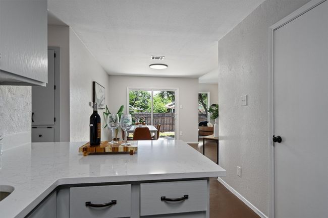 Kitchen with a peninsula, light stone countertops, and a textured wall | Image 11