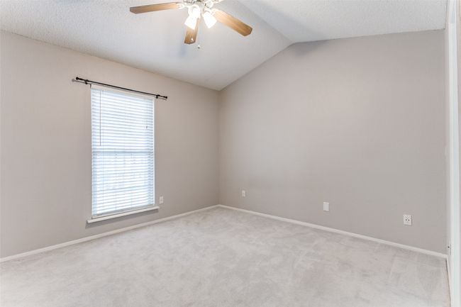 Spare room featuring healthy amount of natural light, a ceiling fan, light carpet, vaulted ceiling, and a textured ceiling | Image 19