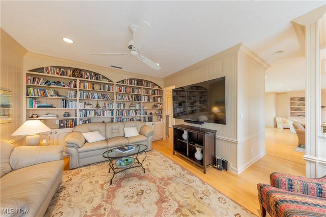 Den featuring wood finished floors, a ceiling fan, visible vents, and built in shelves | Image 26