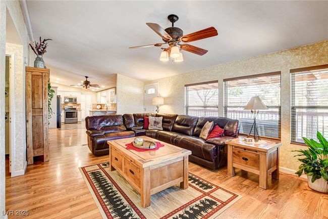 Living room with a ceiling fan, light wood-type flooring, and wallpapered walls | Image 10