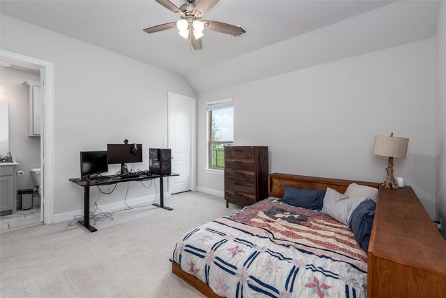 Bedroom with light colored carpet, baseboards, lofted ceiling, a desk, and a ceiling fan | Image 24