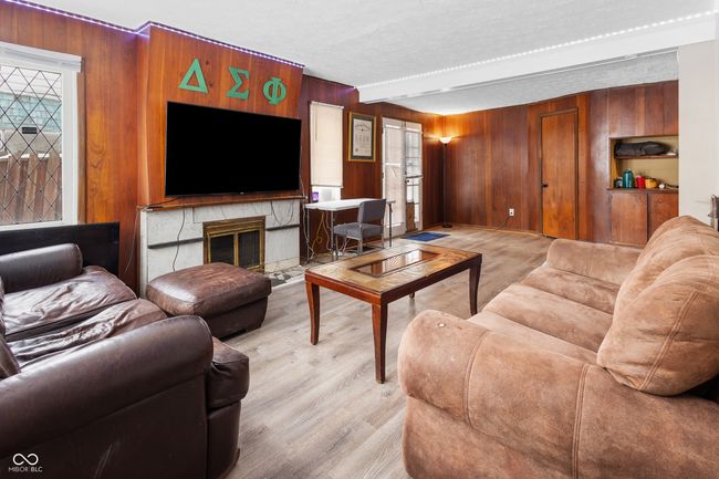 living room with light wood finished floors, plenty of natural light, and wood walls | Image 15