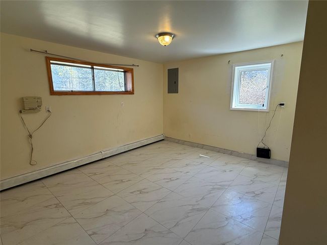 Spare room featuring electric panel, baseboard heating, marble finish floor, and a wealth of natural light | Image 13