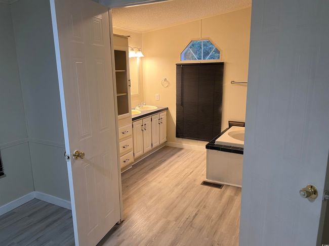 Unfurnished room featuring light wood-type flooring, a ceiling fan, a textured ceiling, baseboards, and a sink | Image 19