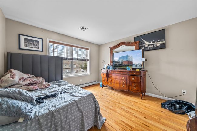 Bedroom featuring baseboard heating, wood finished floors, baseboards, and visible vents | Image 36