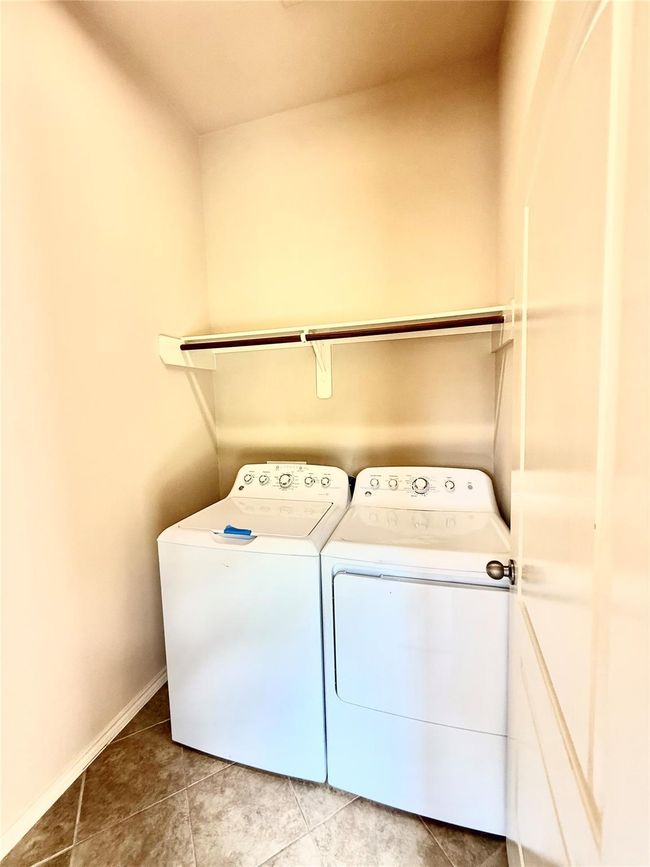 Laundry room with a washer and dryer set, tiled flooring, and a shelf above the appliances for storage. | Image 20