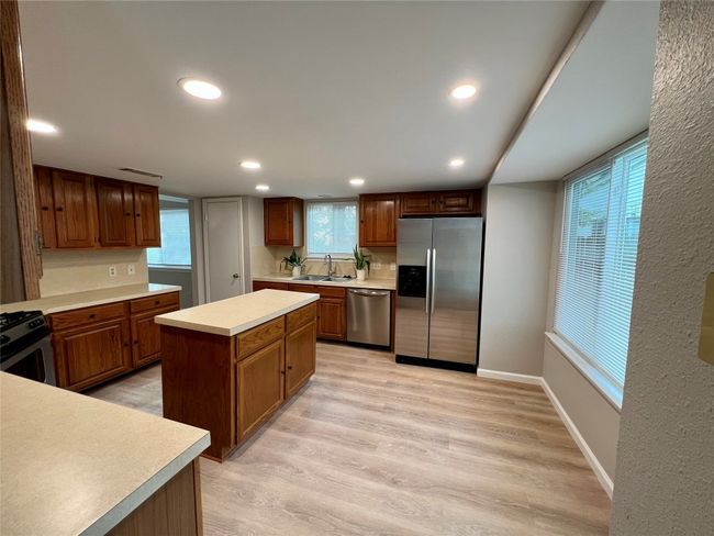 Kitchen with stainless steel appliances, light countertops, light wood finished floors, recessed lighting, and baseboards | Image 9