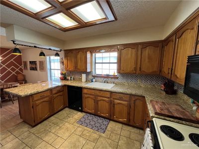 Kitchen with sink, kitchen peninsula, decorative light fixtures, black appliances, and decorative backsplash | Image 3