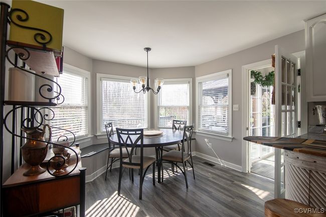 Dining space with dark wood finished floors, a notable chandelier, baseboards, and visible vents | Image 13