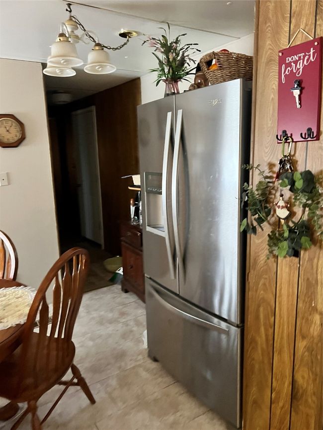 Kitchen with freestanding refrigerator, a chandelier, and light flooring | Image 26
