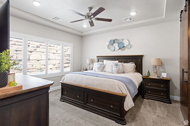 Bedroom featuring light colored carpet, a tray ceiling, ceiling fan, and recessed lighting | Image 36